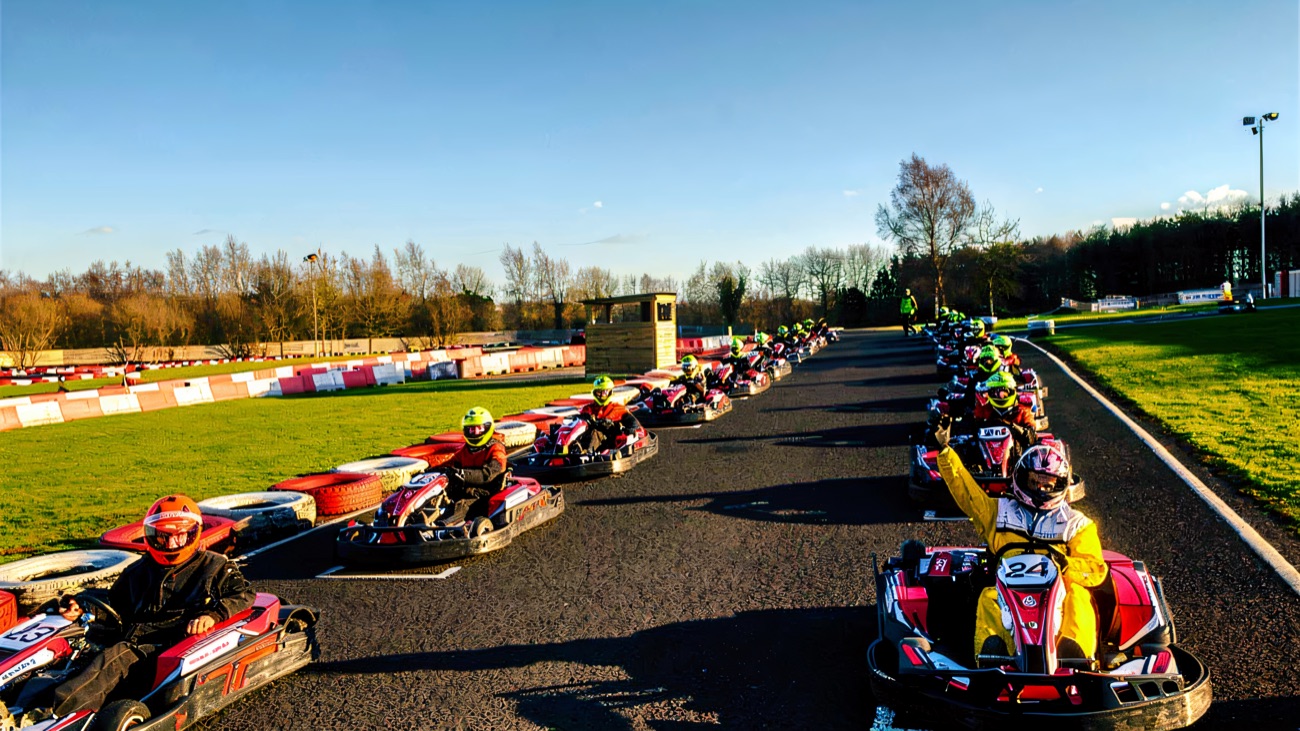 A full grid lined up along the start straight on a crisp blue-sky day