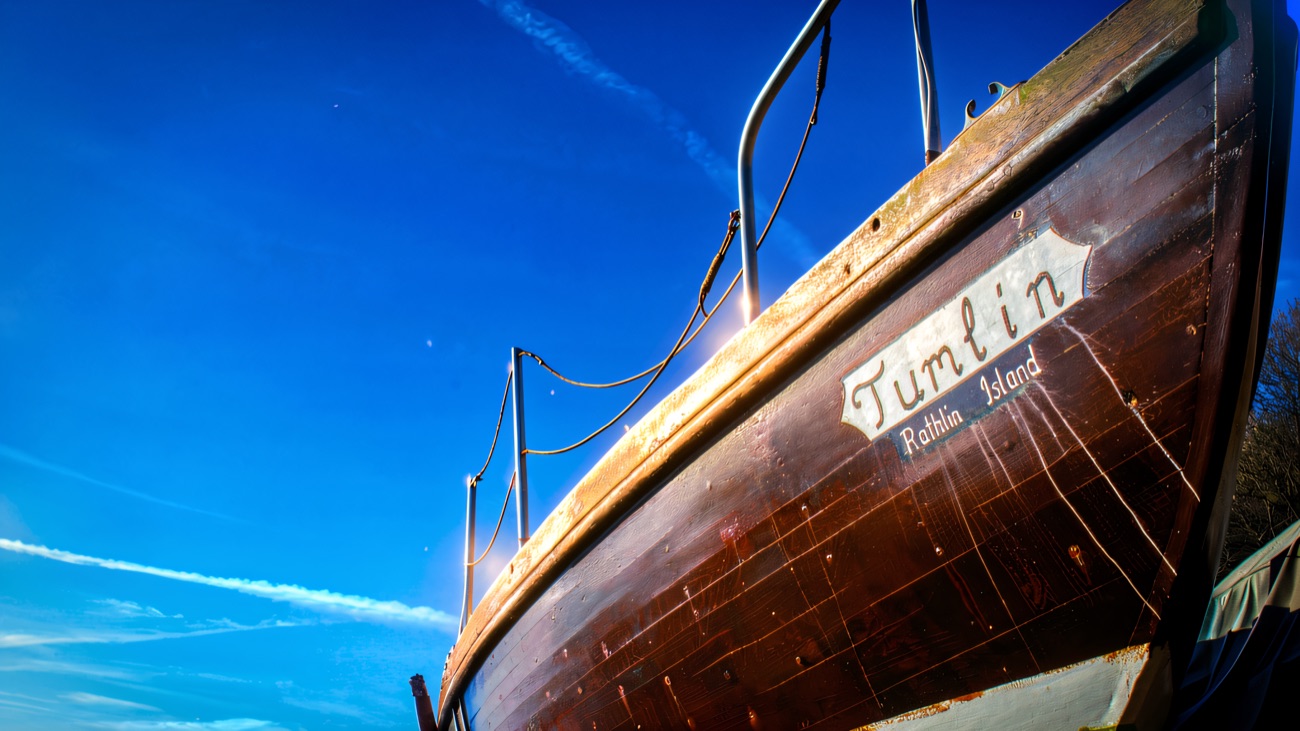 The Rathlin Island boat Tumlin drawn up under a clear blue sky.