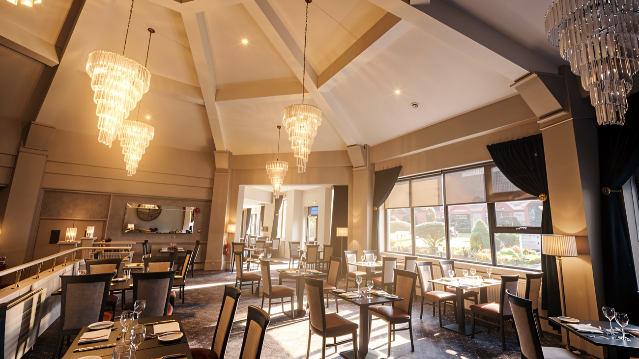 A bright resort dining room with tall ceilings and chandeliers.