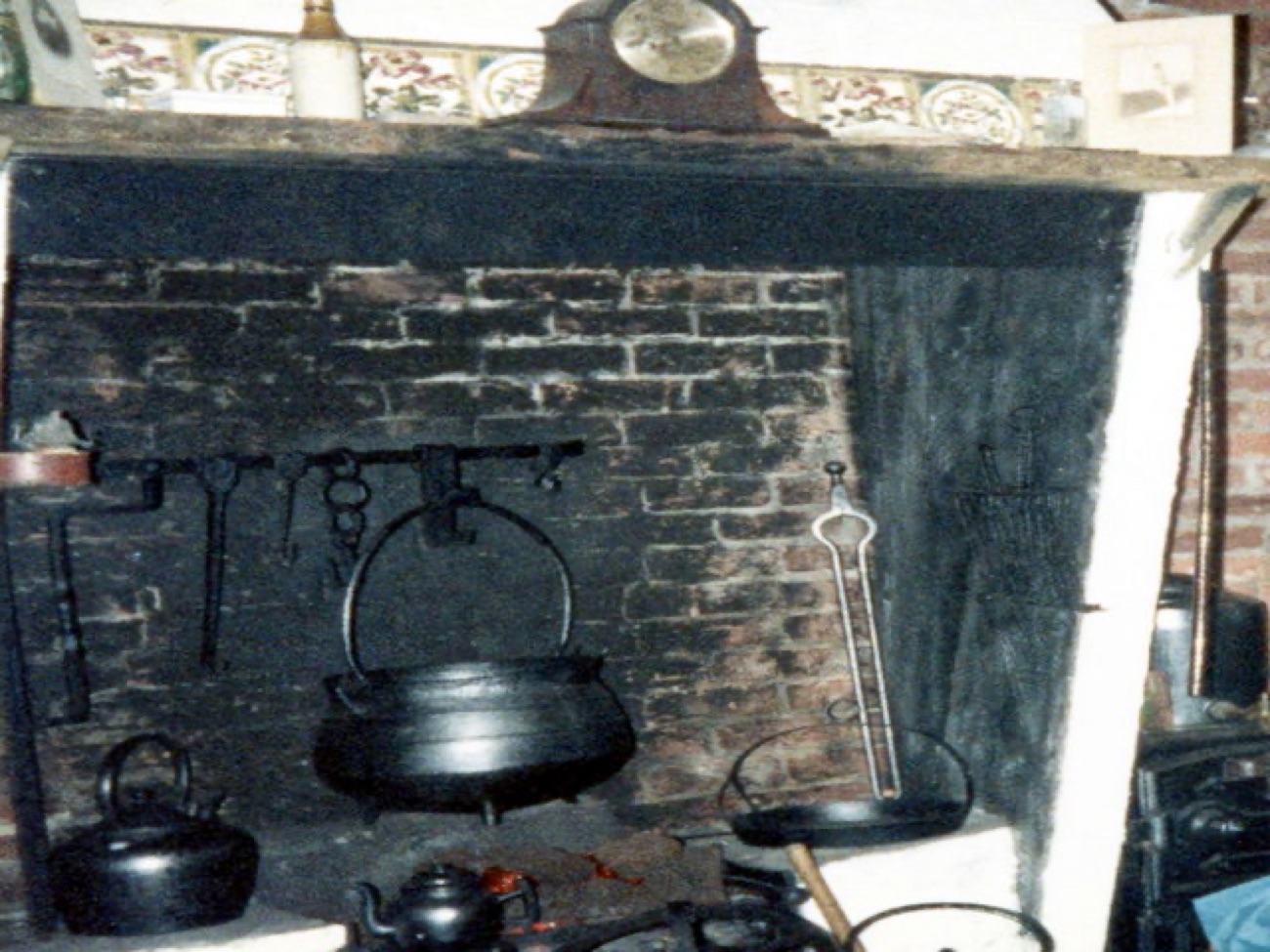 Inside the countryside museum, an old open fireplace with a cast-iron pot and mill equipment.