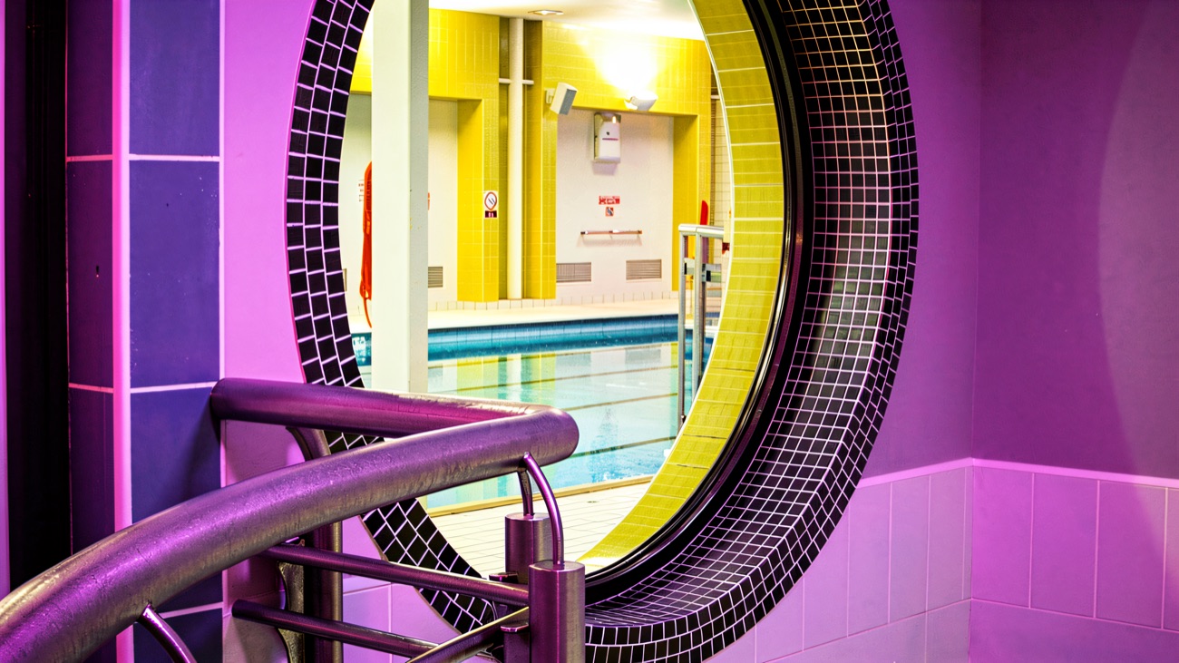 Bright pink and purple poolside area with a round window looking through to the pool