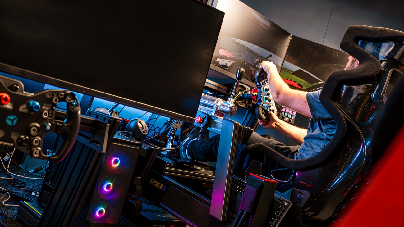 Hands on the wheel in a full racing simulator, track on the screens