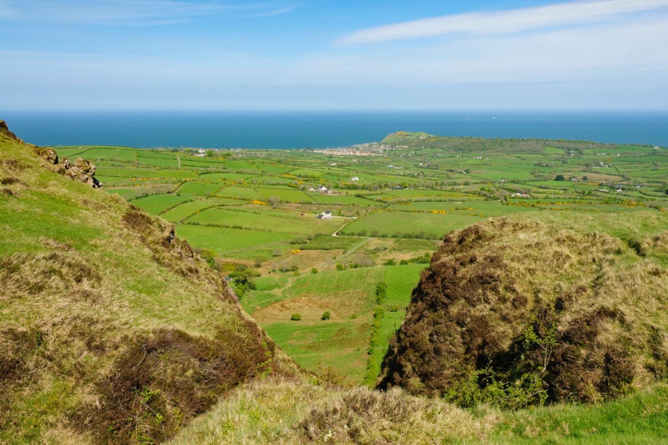 A huge view from the hills down over green fields and hedgerows to the coast and the sea