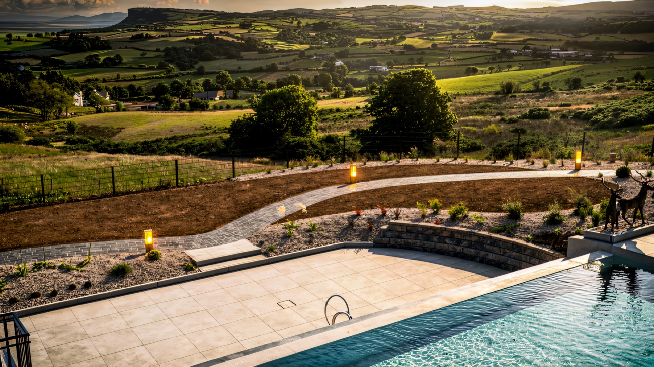 The heated outdoor infinity pool set above a patchwork of green Antrim fields running down to the sea.