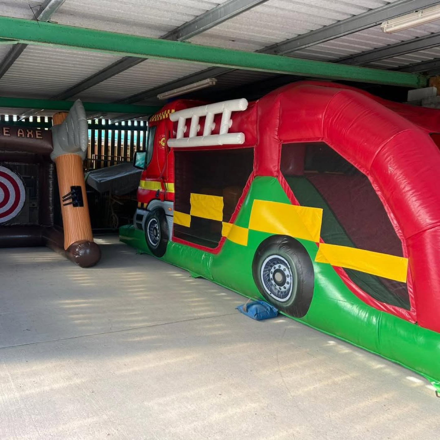 A large inflatable fire-engine obstacle course under a covered play area at Scallywags in Lurgan, with an inflatable axe-throwing game beside it