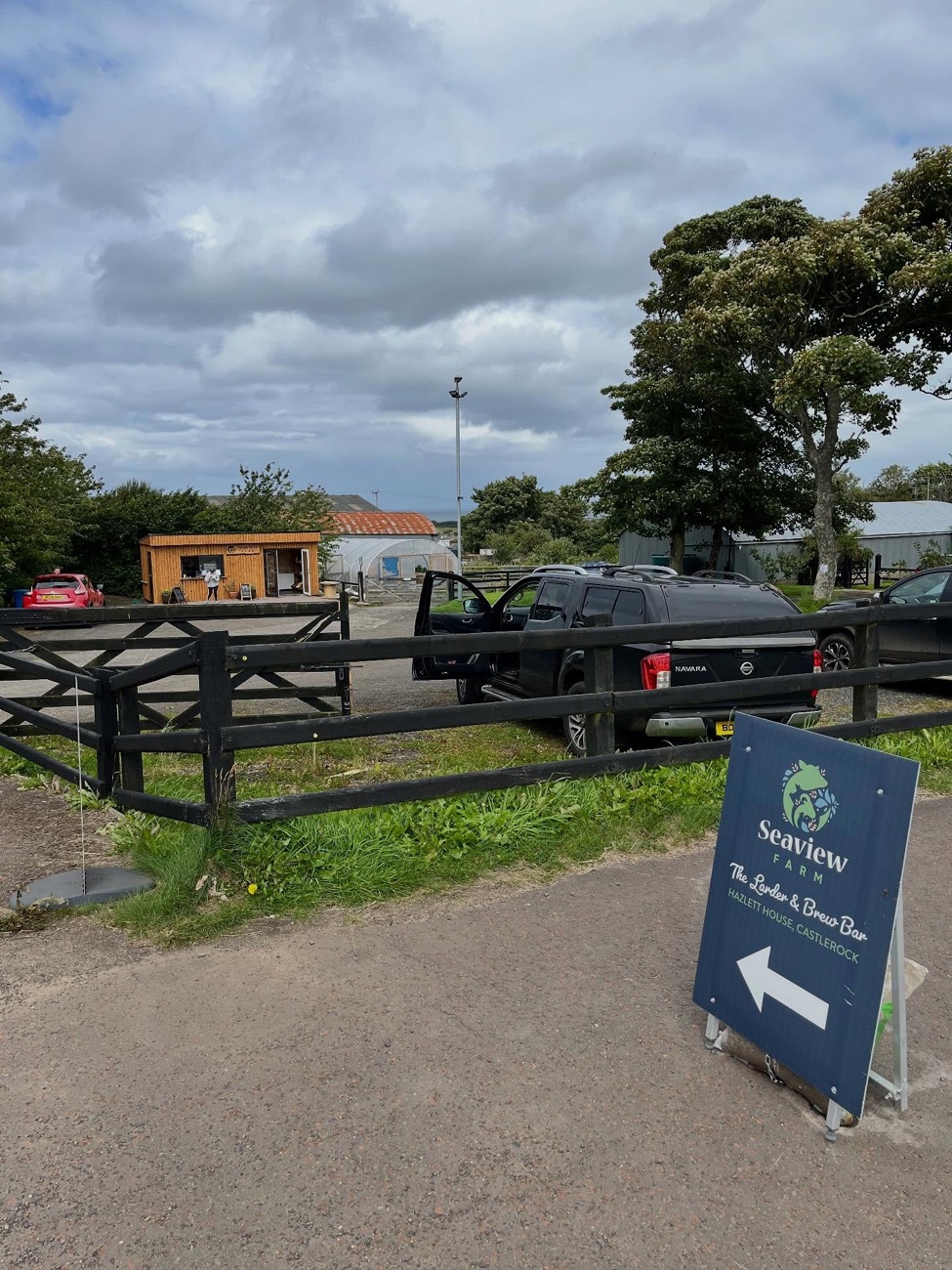 The entrance to Seaview Farm with the Larder & Brew Bar sign, the cabin and polytunnel beyond