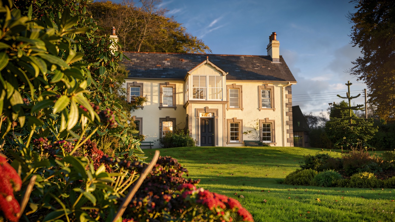 The house in autumn light, its lawns and borders sloping away to the front.