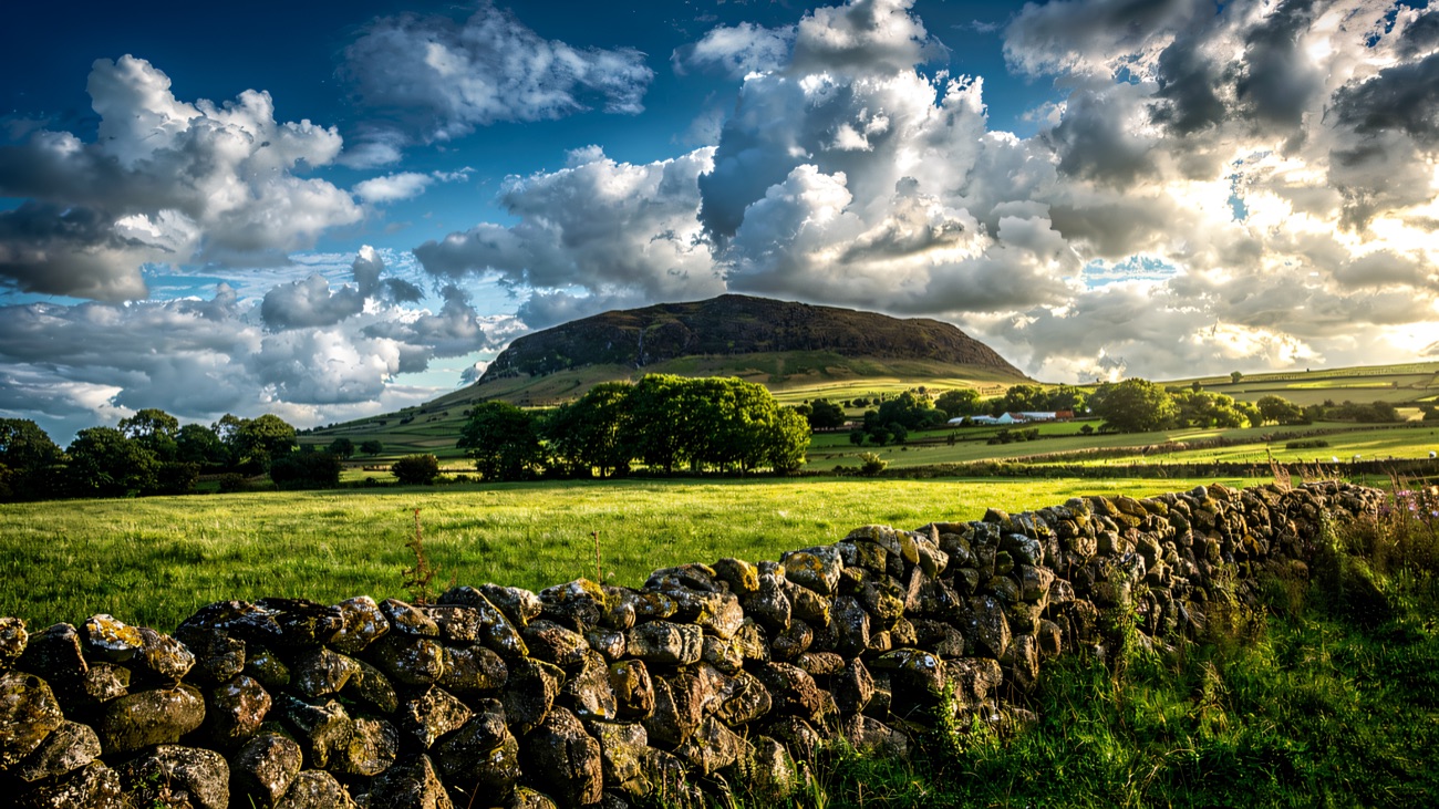 The classic conical hill above a mossy dry-stone wall and big summer sky