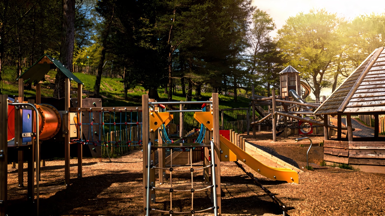 The colourful adventure playpark with climbing frames, a slide and a wooden play pod set among the forest trees