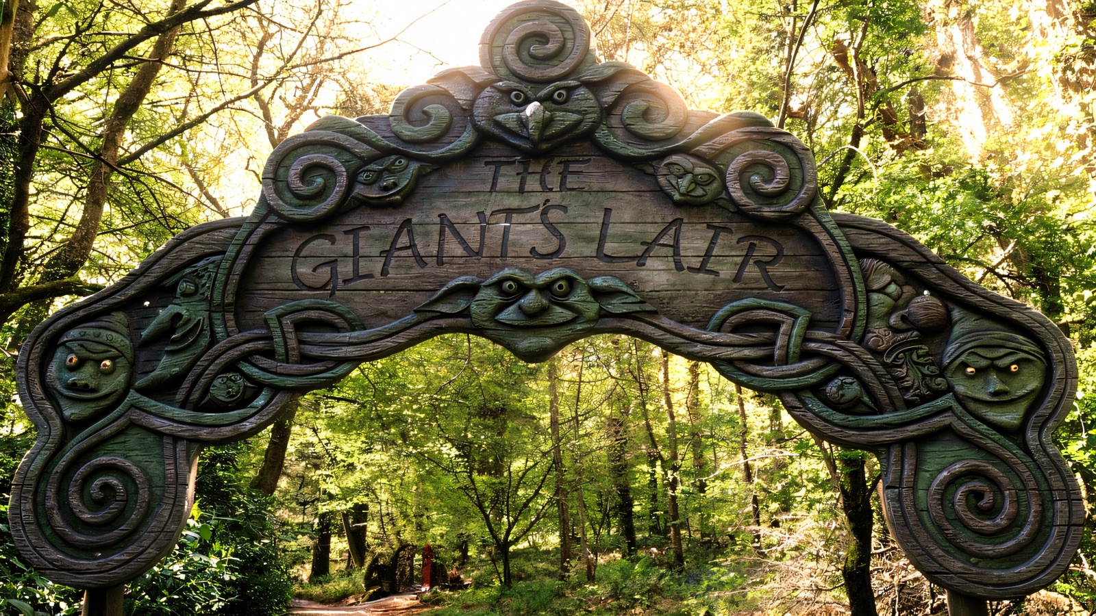 The carved wooden 'The Giant's Lair' archway with faces and Celtic knotwork over the woodland path into Fionn's Giant Adventure