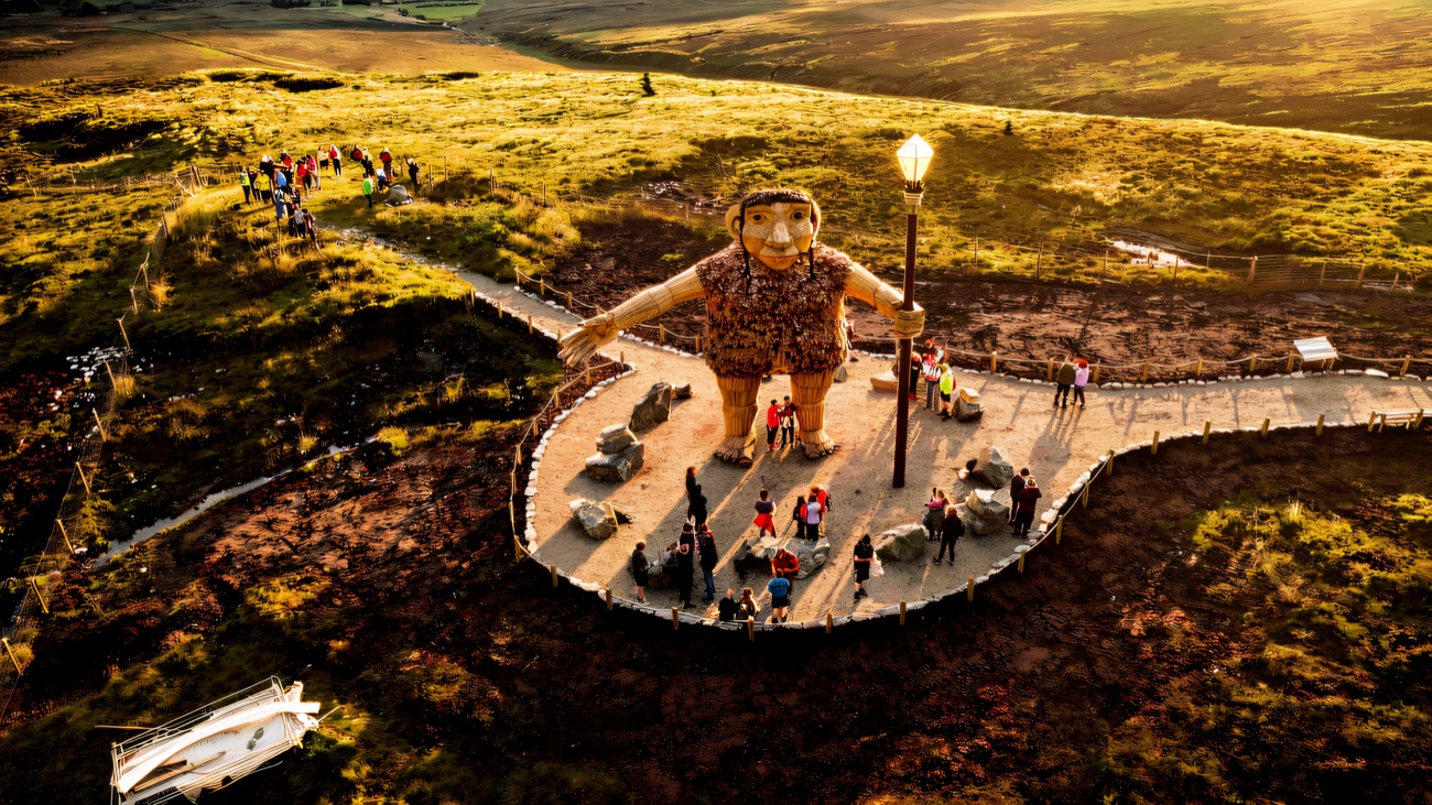 An elevated view showing the scale of the figure, visitors small around his feet.
