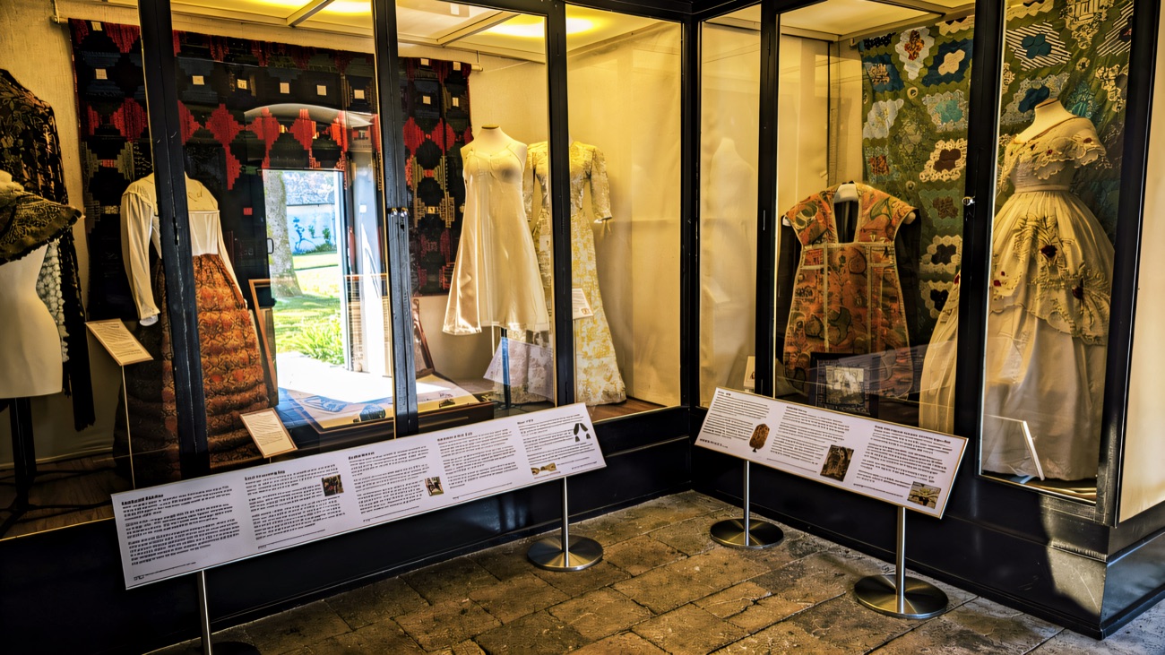 Glass display cases in the costume collection at Springhill, filled with period dresses and quilts