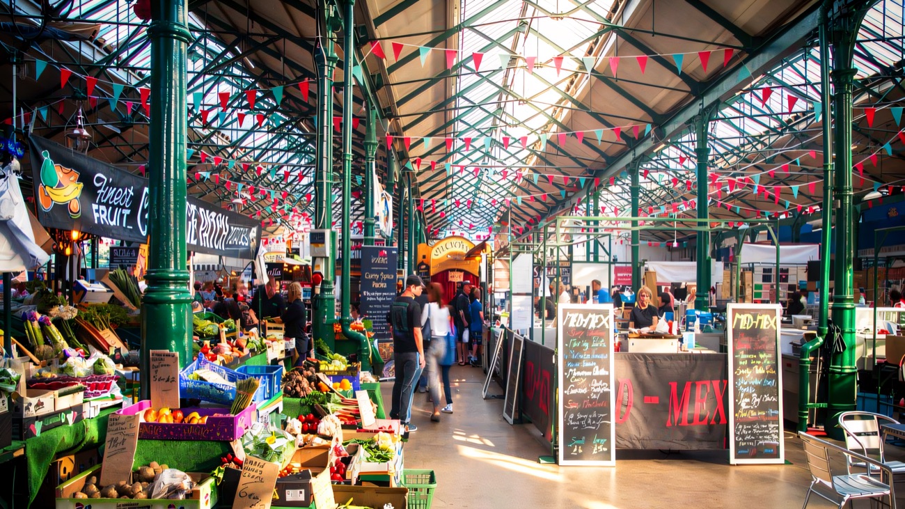 Produce and craft stalls under the iron-and-glass roof with bunting strung overhead at St George's Market