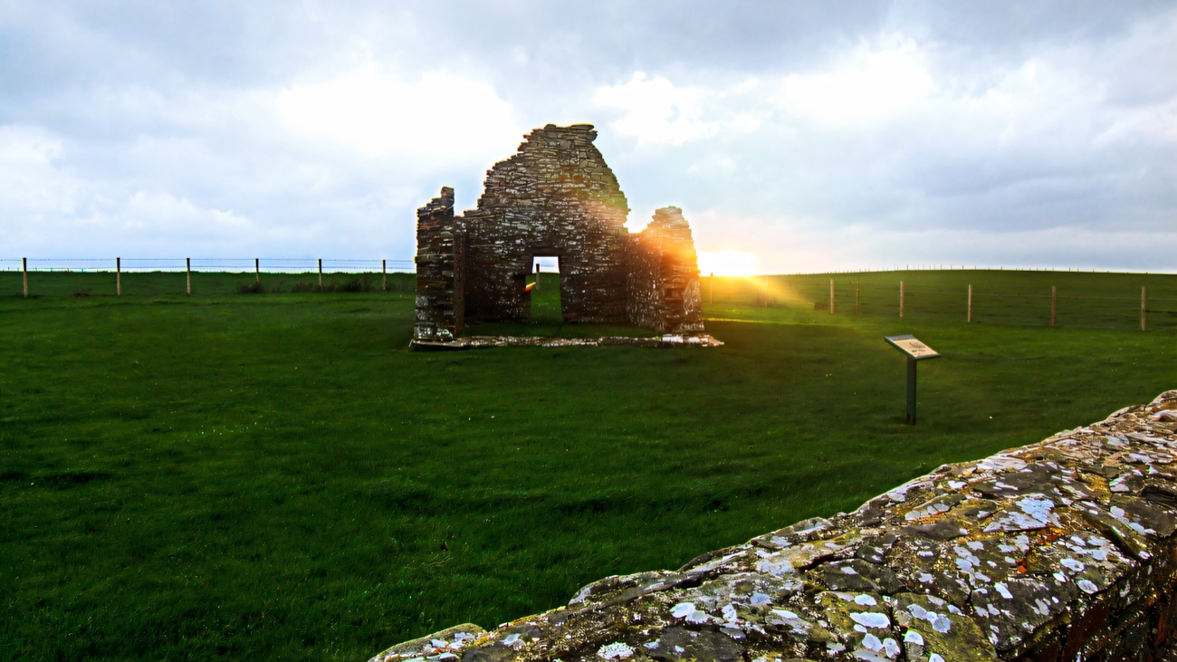 The little early church ruin standing alone in a coastal field, the sea on the horizon.