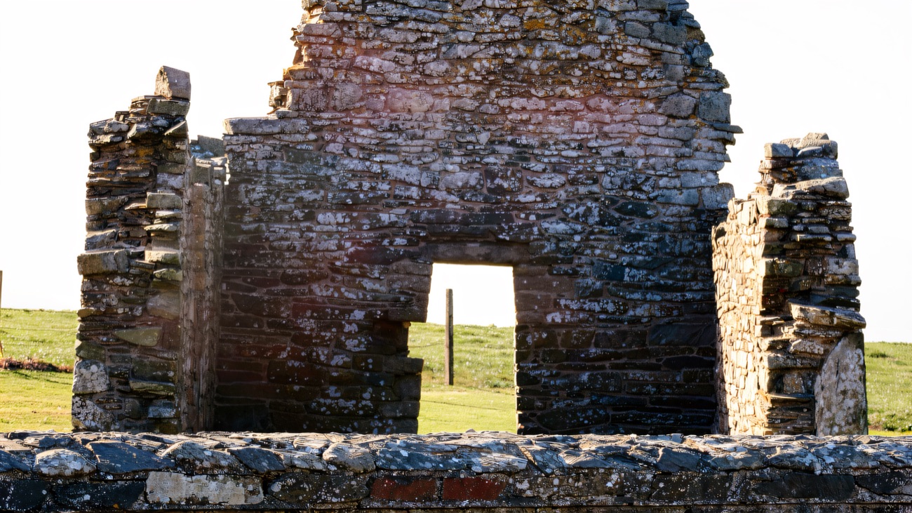 The gable end seen over the enclosure wall, with the projecting side walls of an early Irish church.