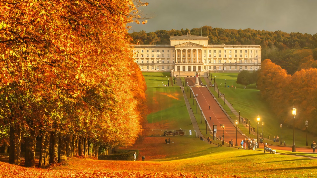 Parliament Buildings across the Stormont estate in autumn, framed by golden trees