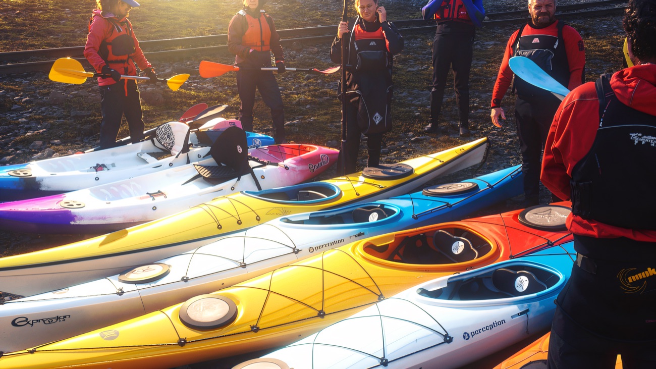 A rainbow of kayaks lined up ready on the shore