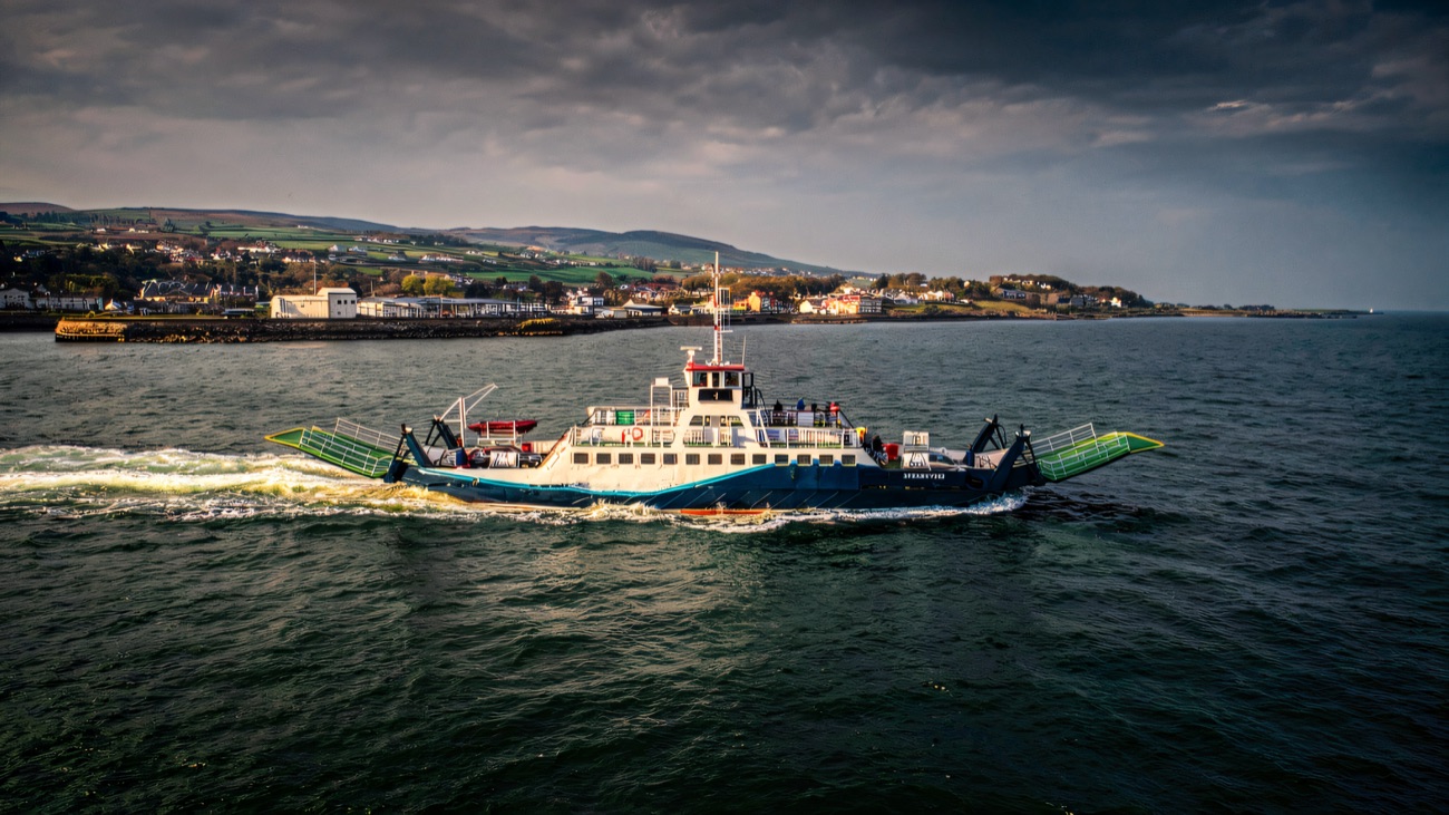 The Strangford ferry underway, seen from above with the village along the shore.