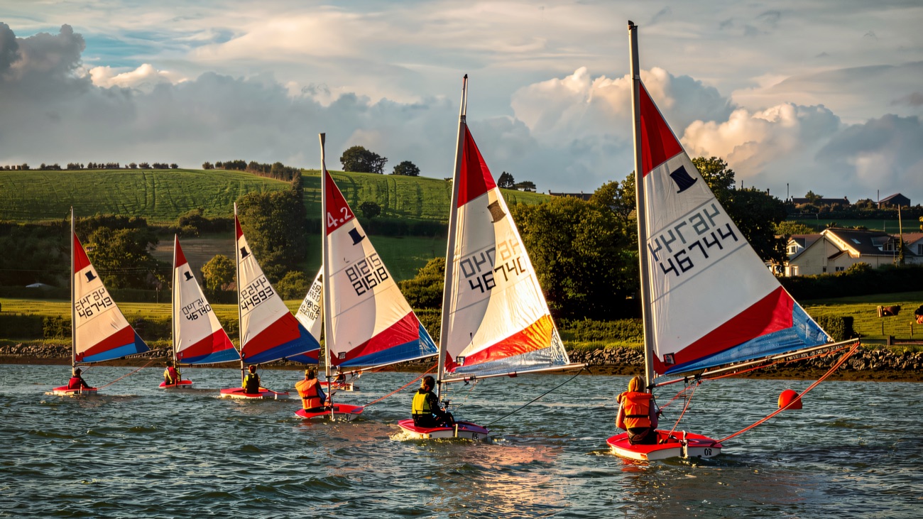 A line of Topper dinghies racing past the green Strangford drumlins