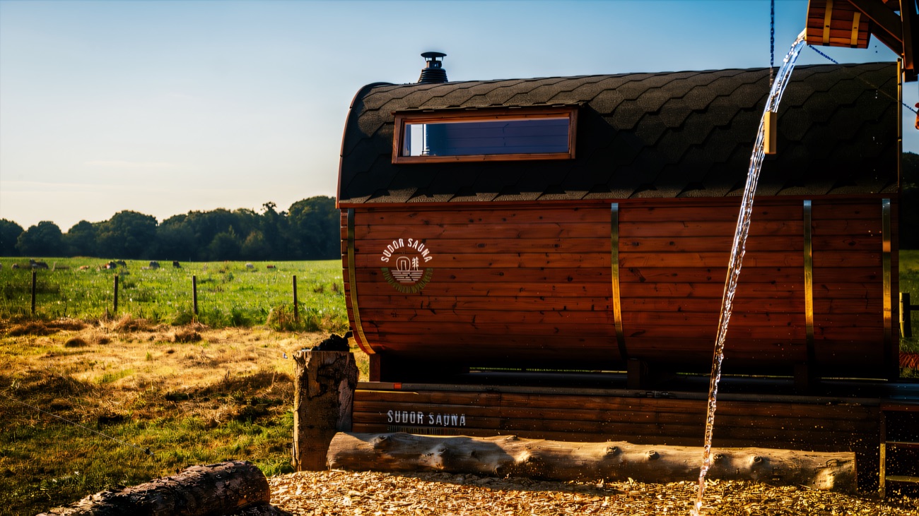 The barrel sauna outdoors with water being poured over the stones