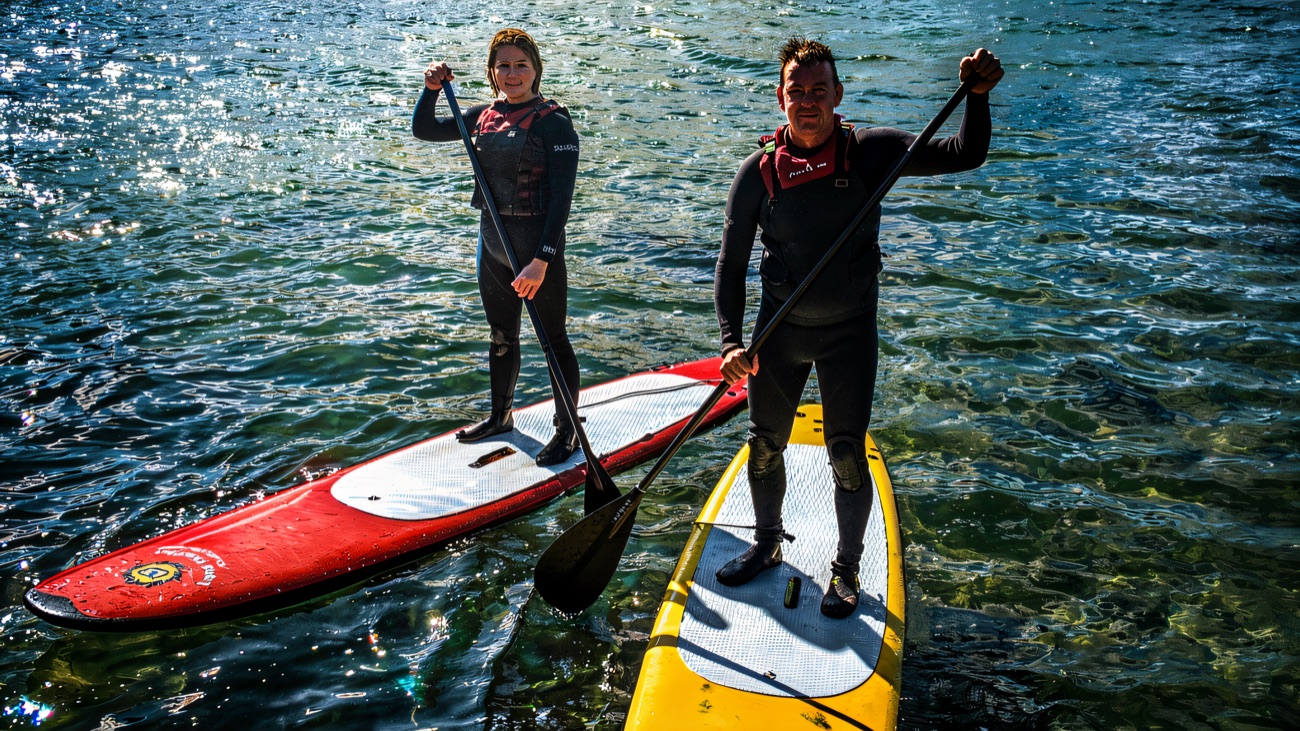Paddleboarders balanced in the calm of Portballintrae harbour