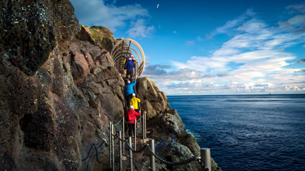 Climbing the tubular bridge staircase along the cliff face above the sea