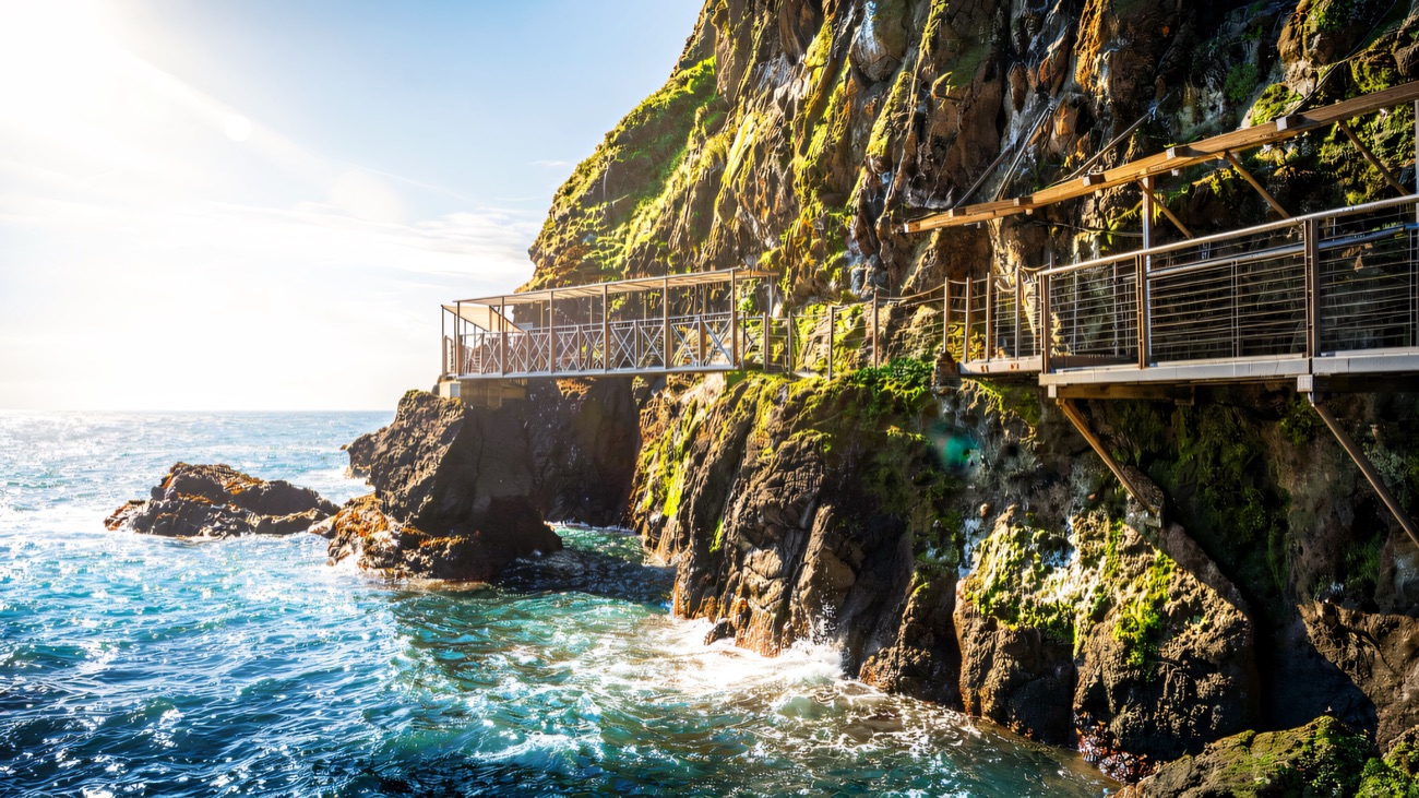 The steel walkway hugging the cliff over turquoise crashing water