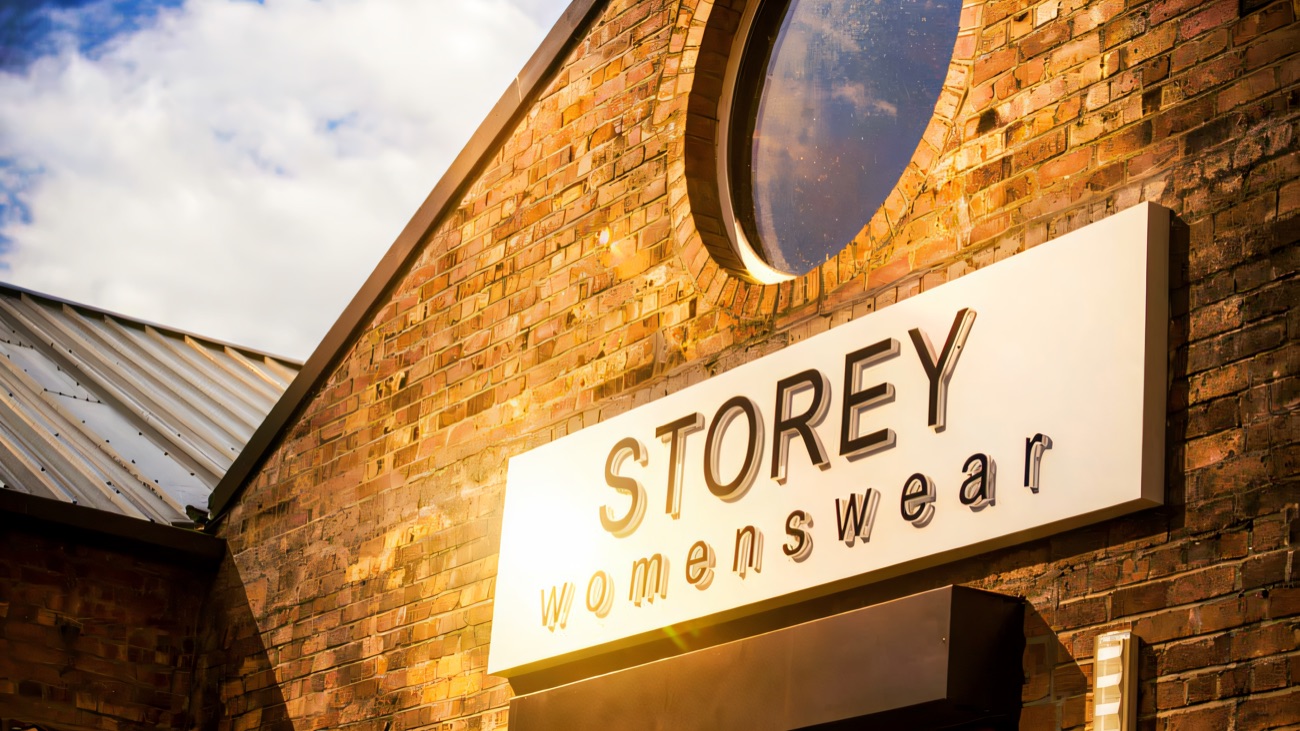 The Storey Womenswear shopfront set in a restored red-brick mill gable, with a round mill window above
