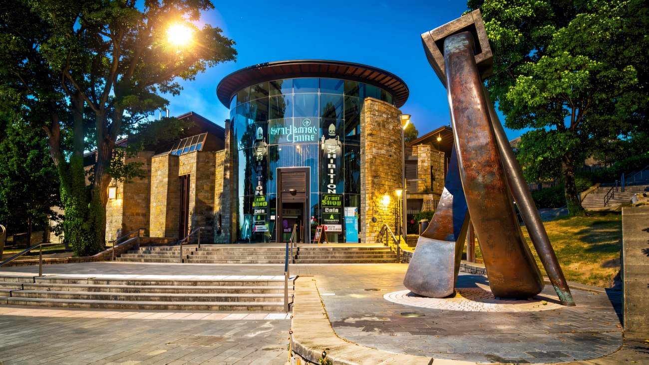 The centre's curved glass rotunda and forecourt, with the bronze bell sculpture out front.