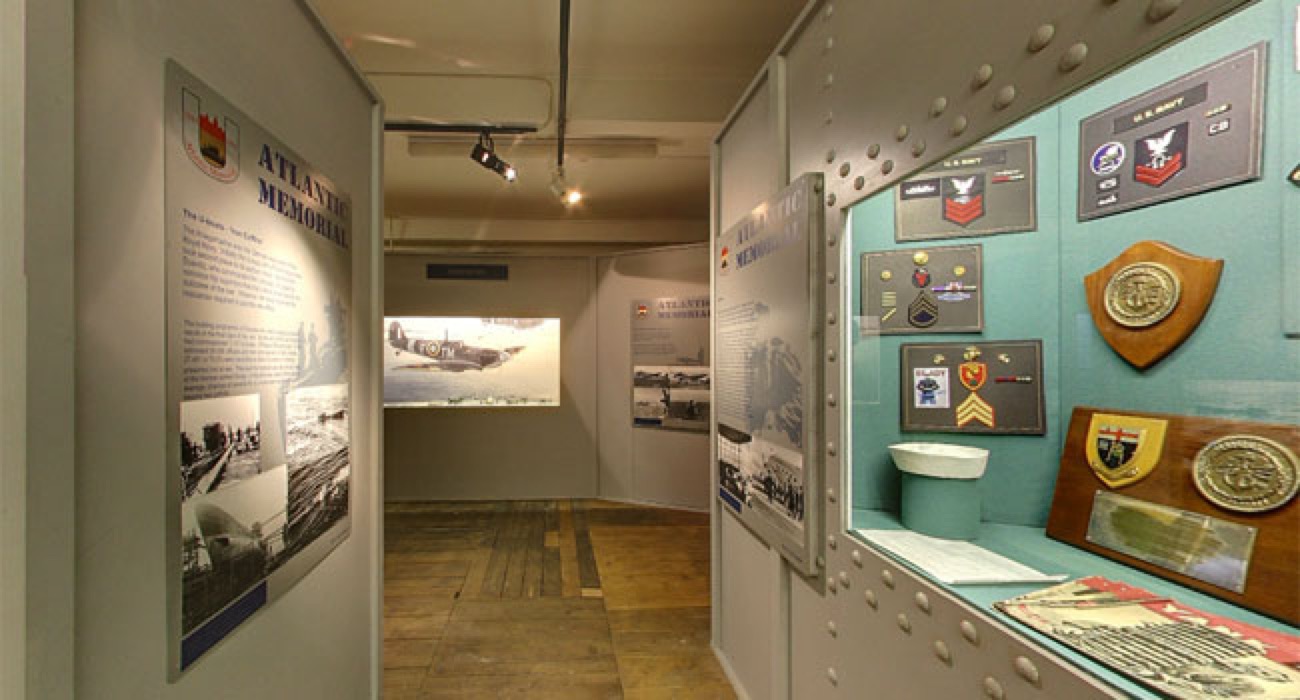 The Atlantic Memorial exhibition inside the museum — storyboards on Derry's role in the Battle of the Atlantic, a display case of naval insignia and a projected image of a Spitfire aircraft