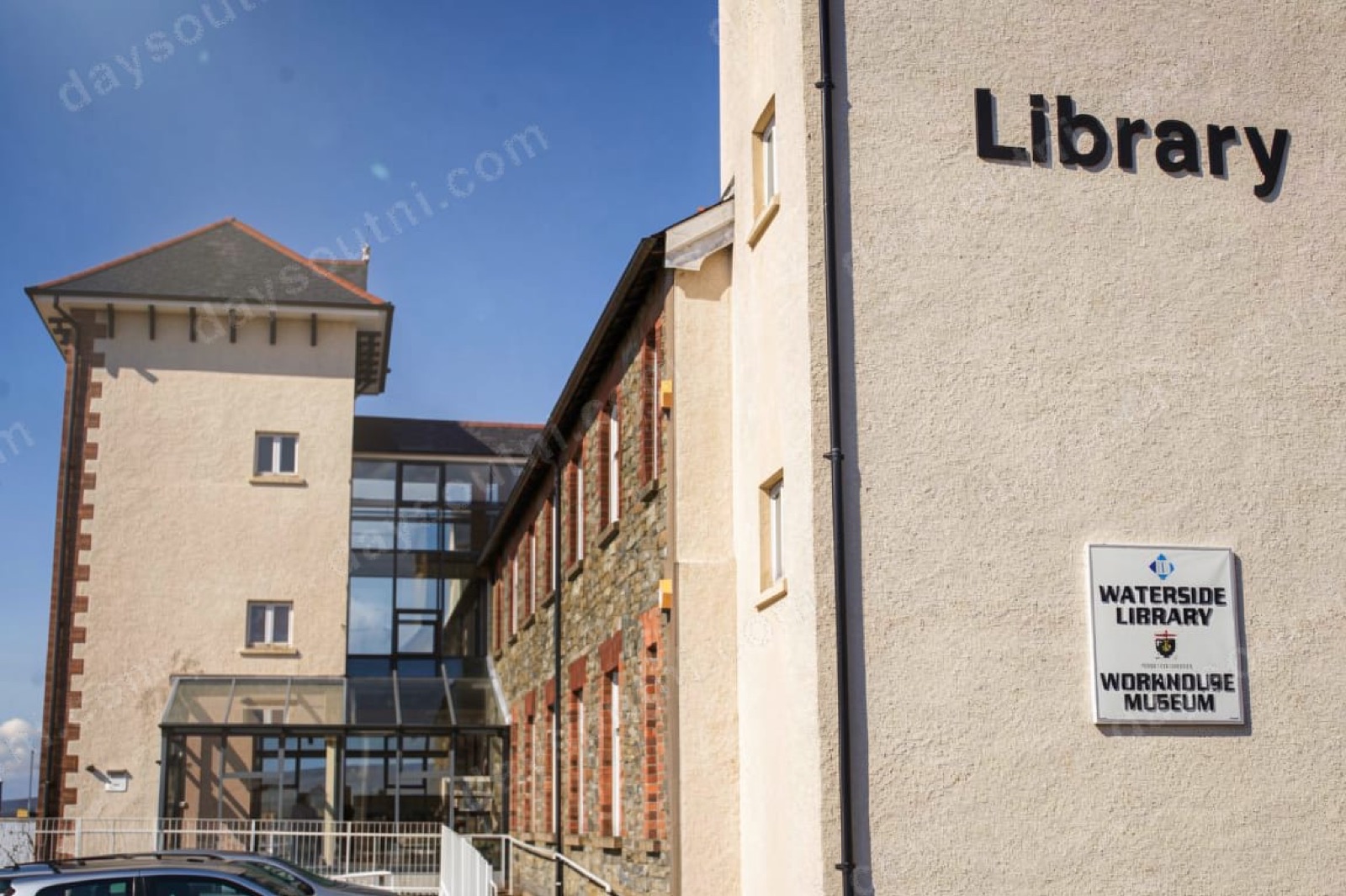 The stone Victorian workhouse building on Glendermott Road, now Waterside Library and the Workhouse Museum, with its square tower and a wall sign reading 'Waterside Library / Workhouse Museum'