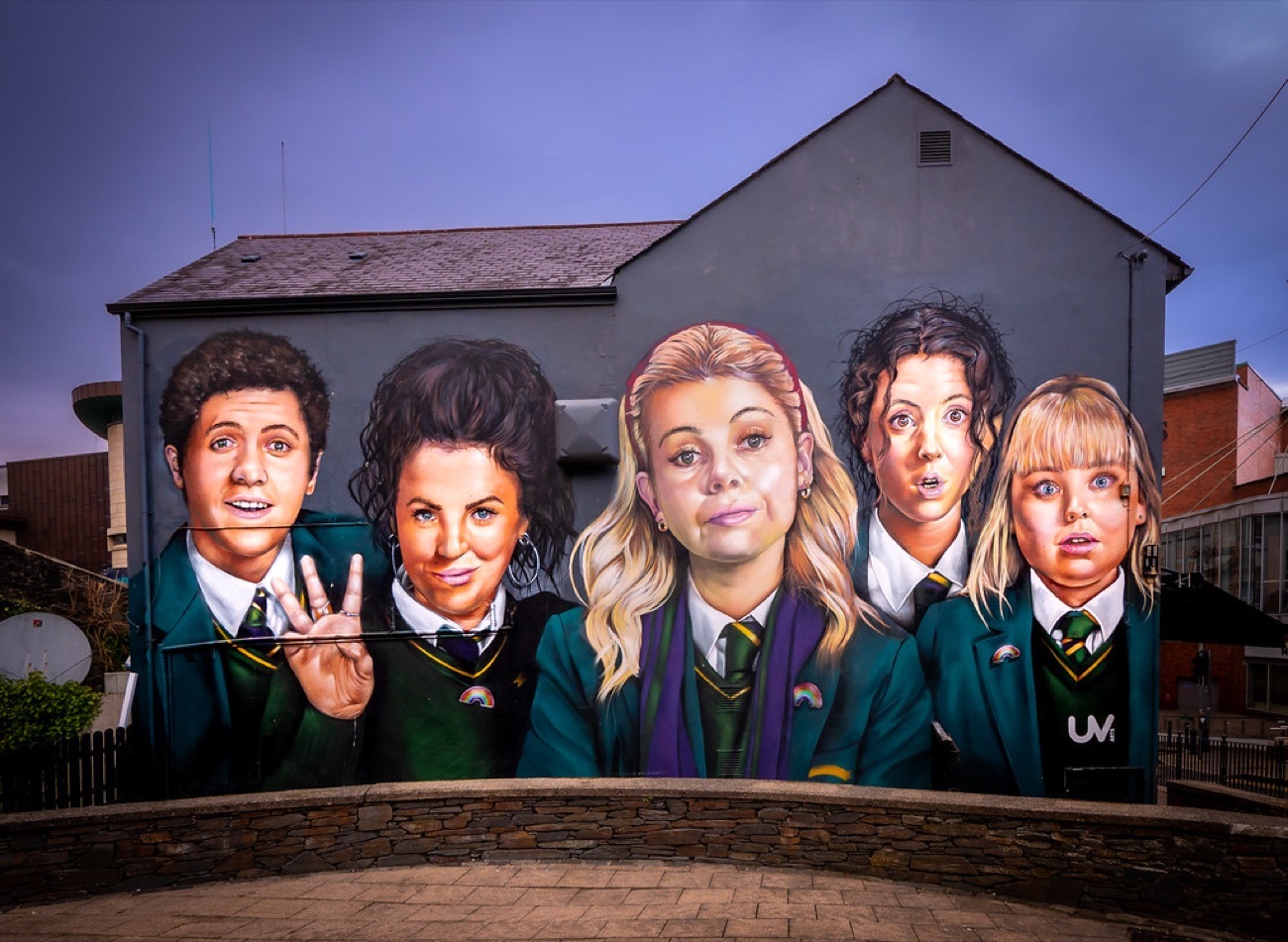 The Derry Girls mural painted two storeys high on the gable wall of Badgers Bar at dusk