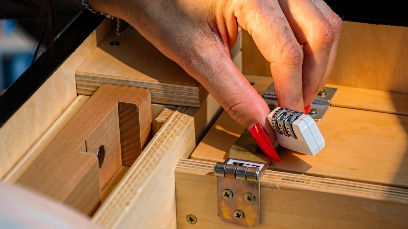 Fingers turning the dials of a combination lock on a wooden case