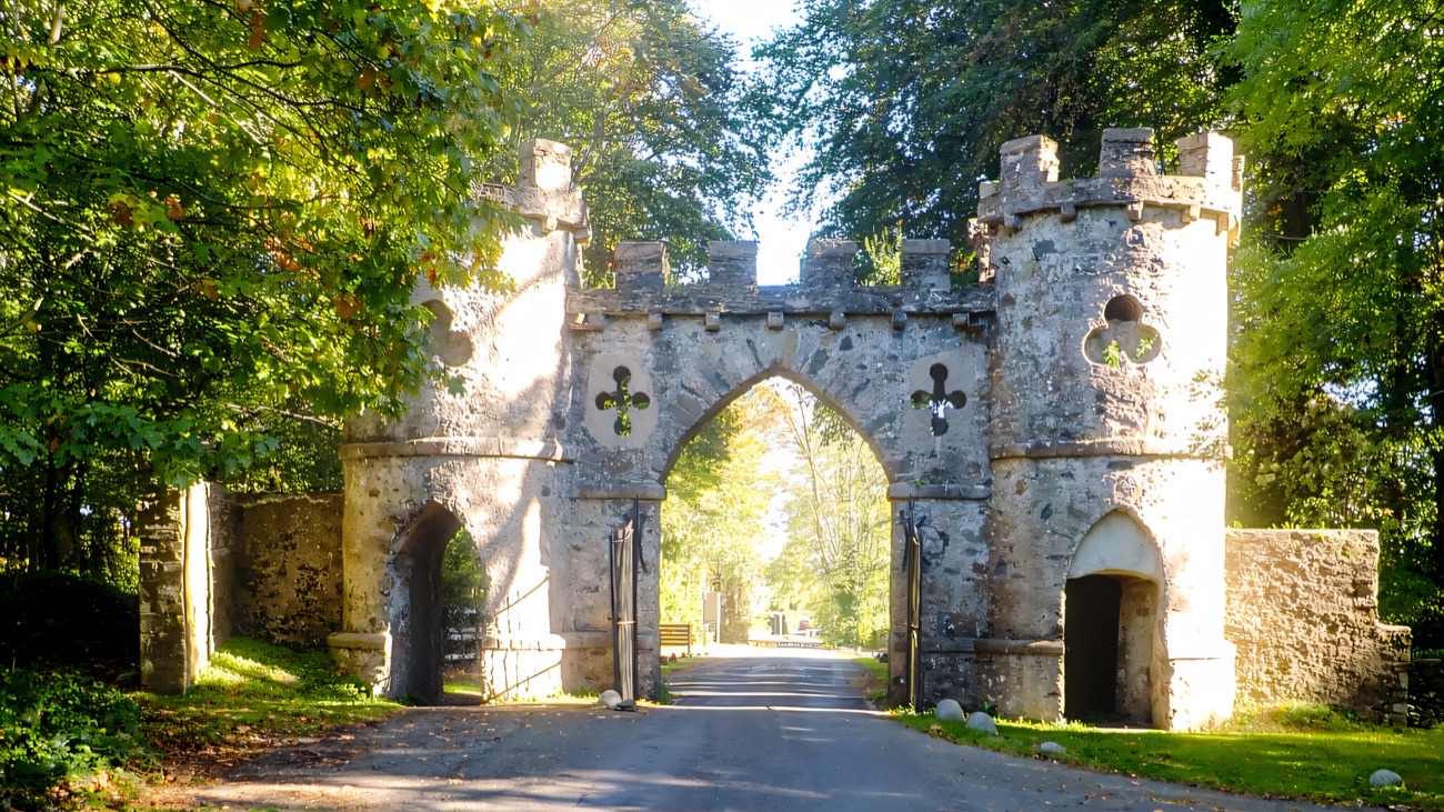 The Barbican — a grey stone castellated gothic gateway arch over the park road, framed by trees