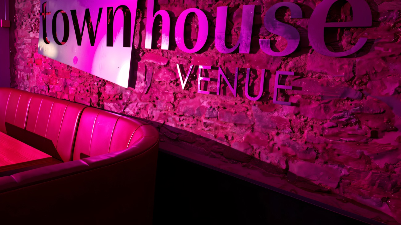 The Townhouse Venue sign lit in pink against the exposed stone wall