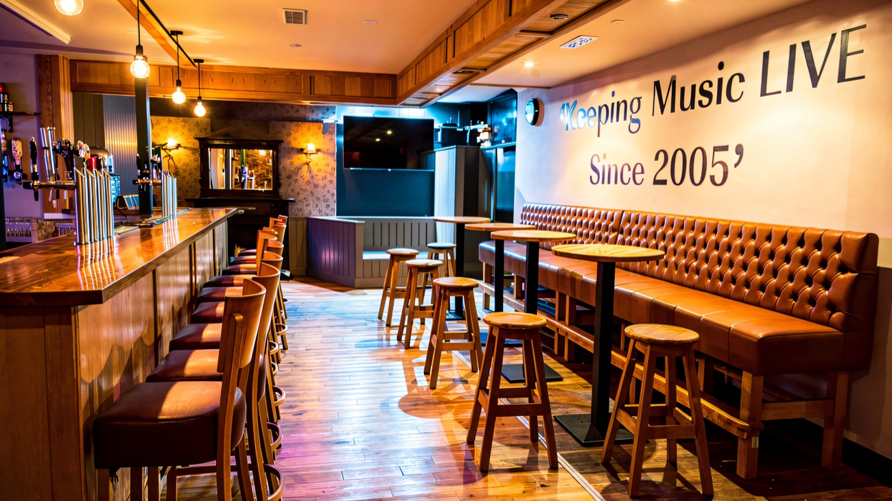 The bar with stools, booth seating and Keeping Music Live painted on the wall