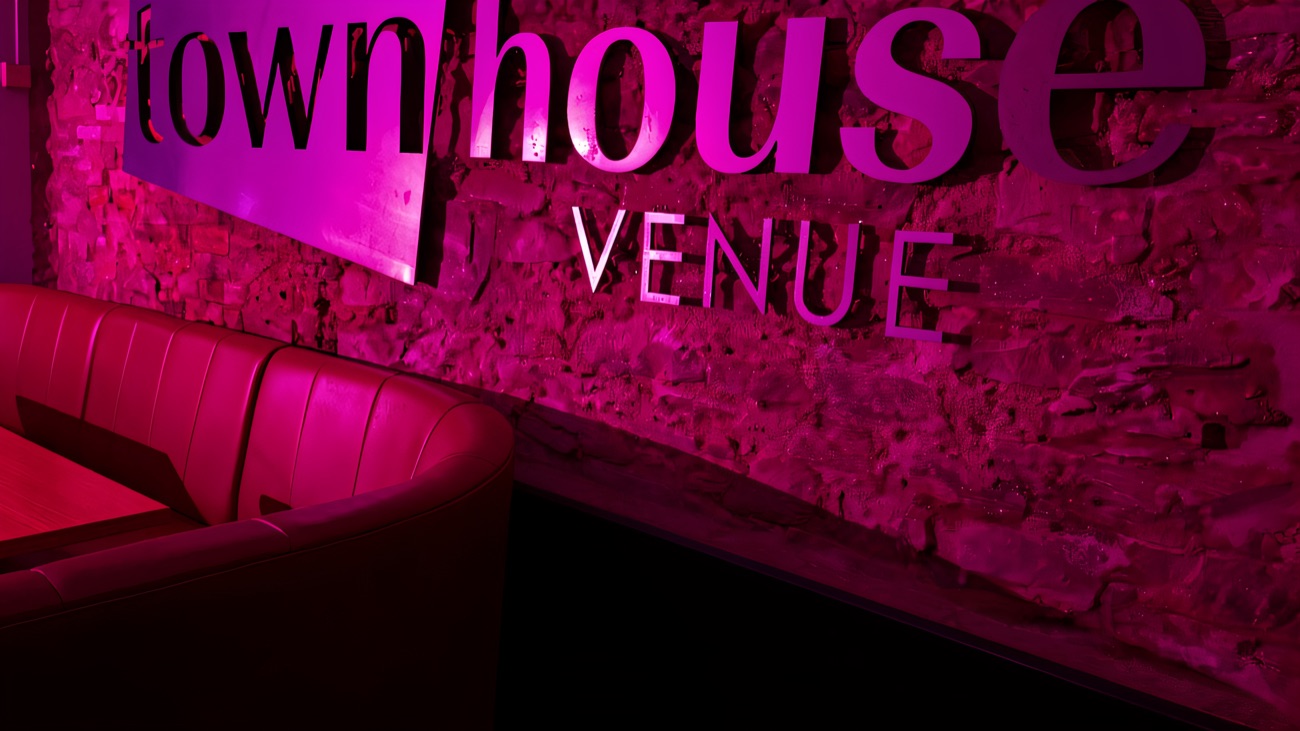 The Townhouse Venue sign on a stone wall under pink lighting