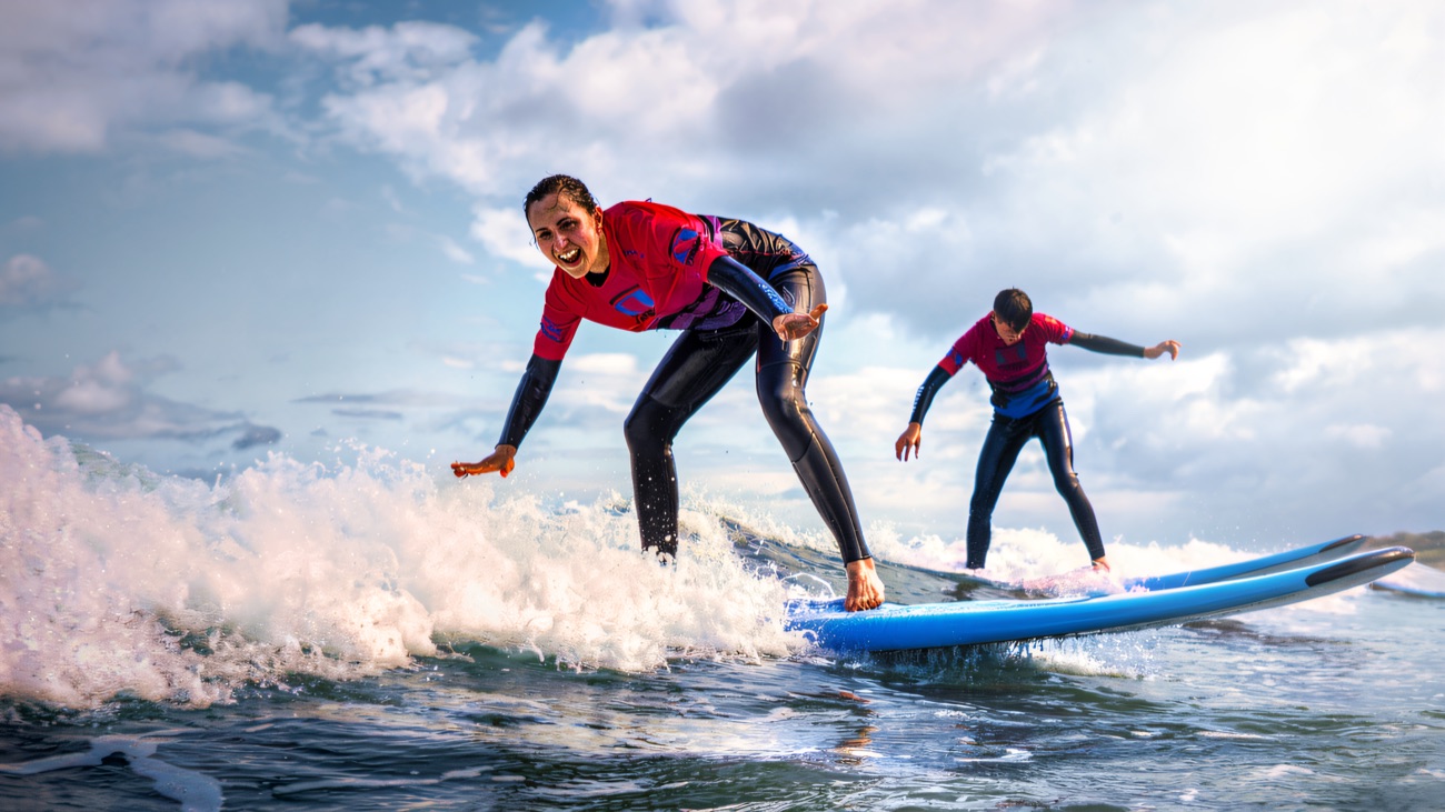 Two riders up and beaming, catching the same wave together