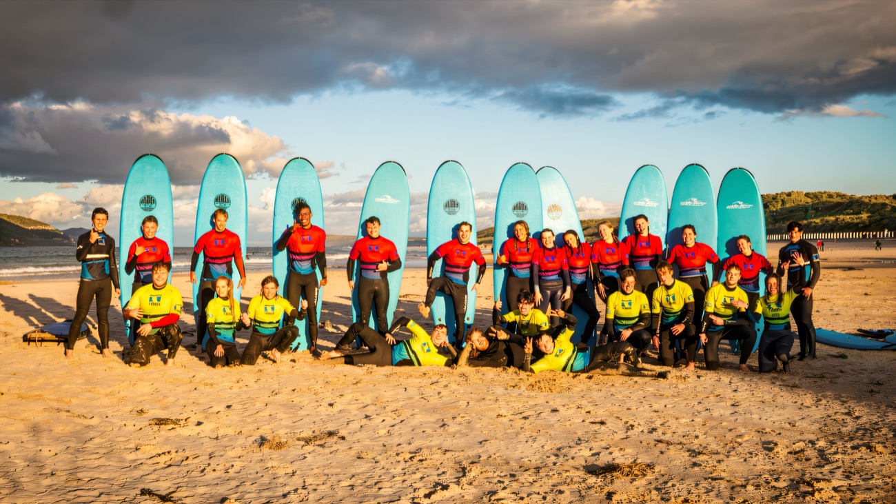 The whole group and their boards on West Strand as golden hour lights up the sky