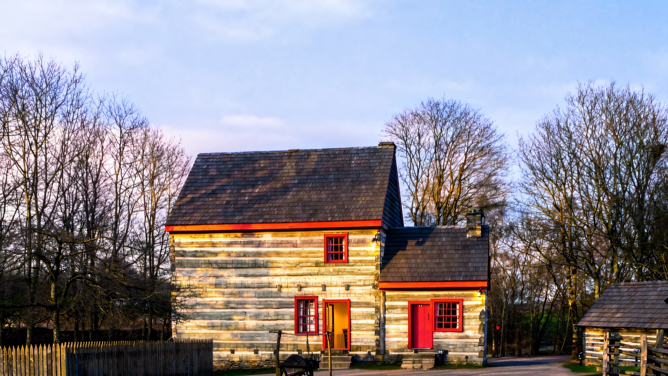 A two-storey timber house with red-painted window frames in the park