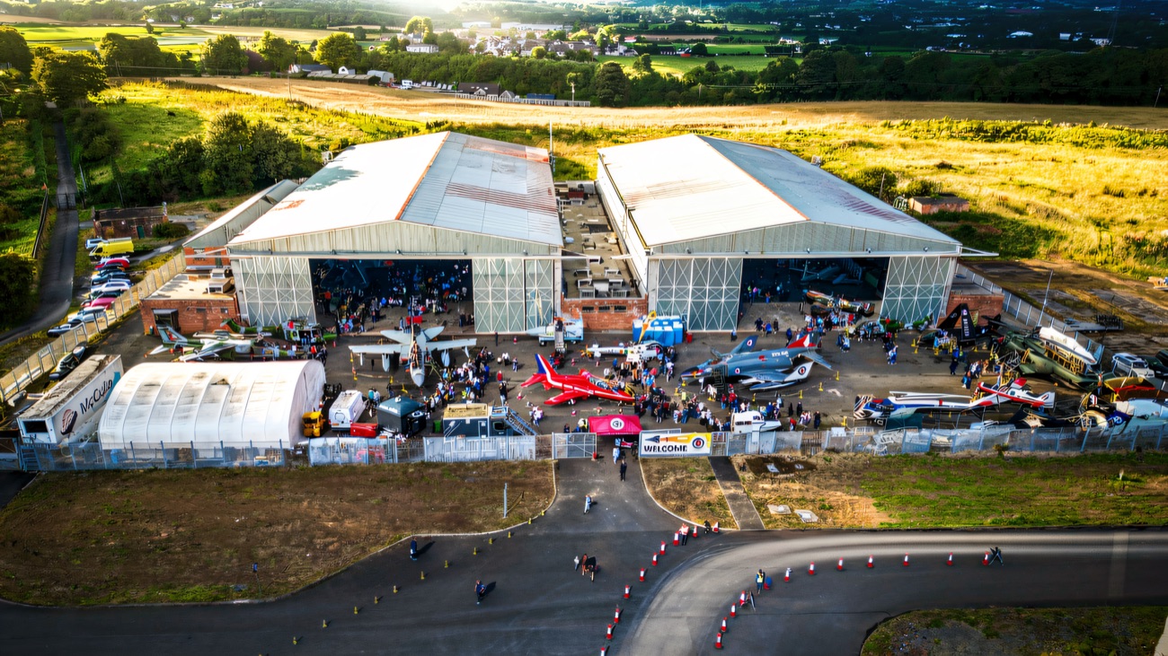 The two big hangars from the air on an open day, with aircraft lined up outside and visitors wandering between them