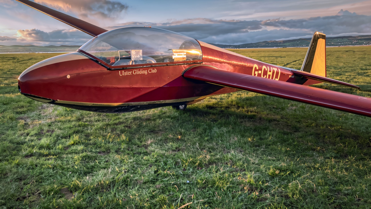 The club's red and cream glider on the grass at Bellarena, with the lough and distant hills catching the evening light