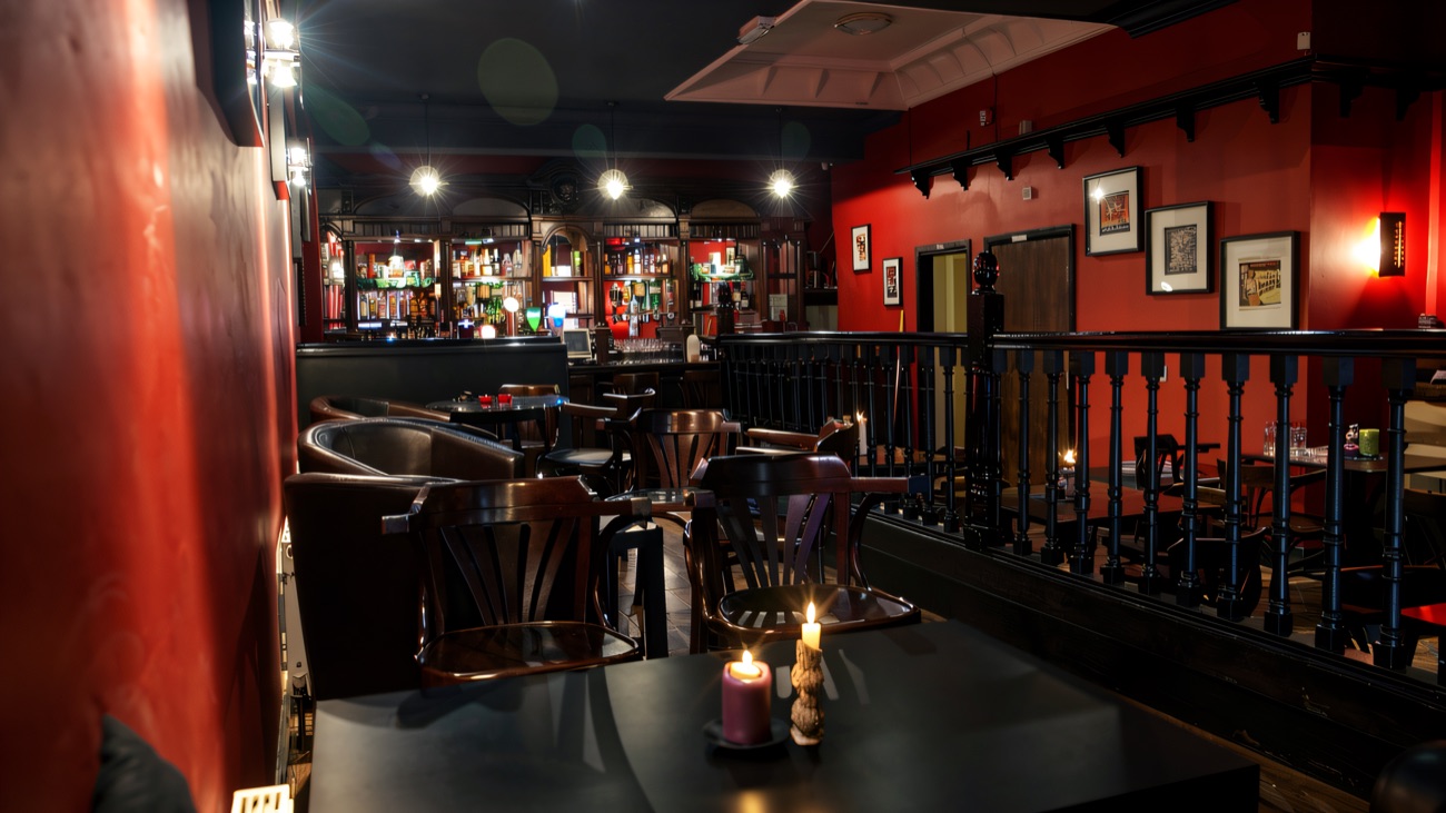 The upstairs bar lit red, with candles on the tables