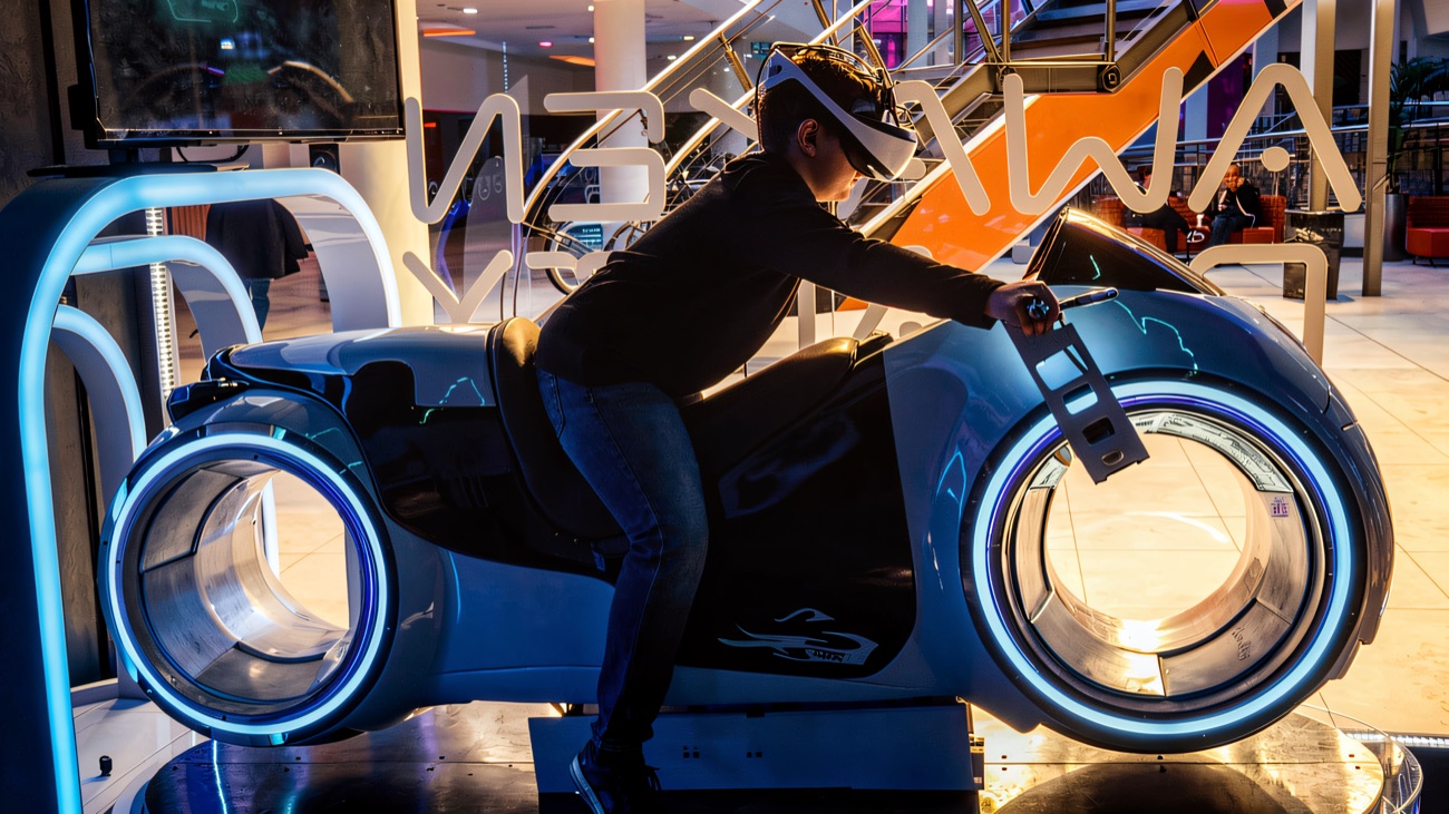 A rider leaning into the VR motorbike simulator on its lit platform