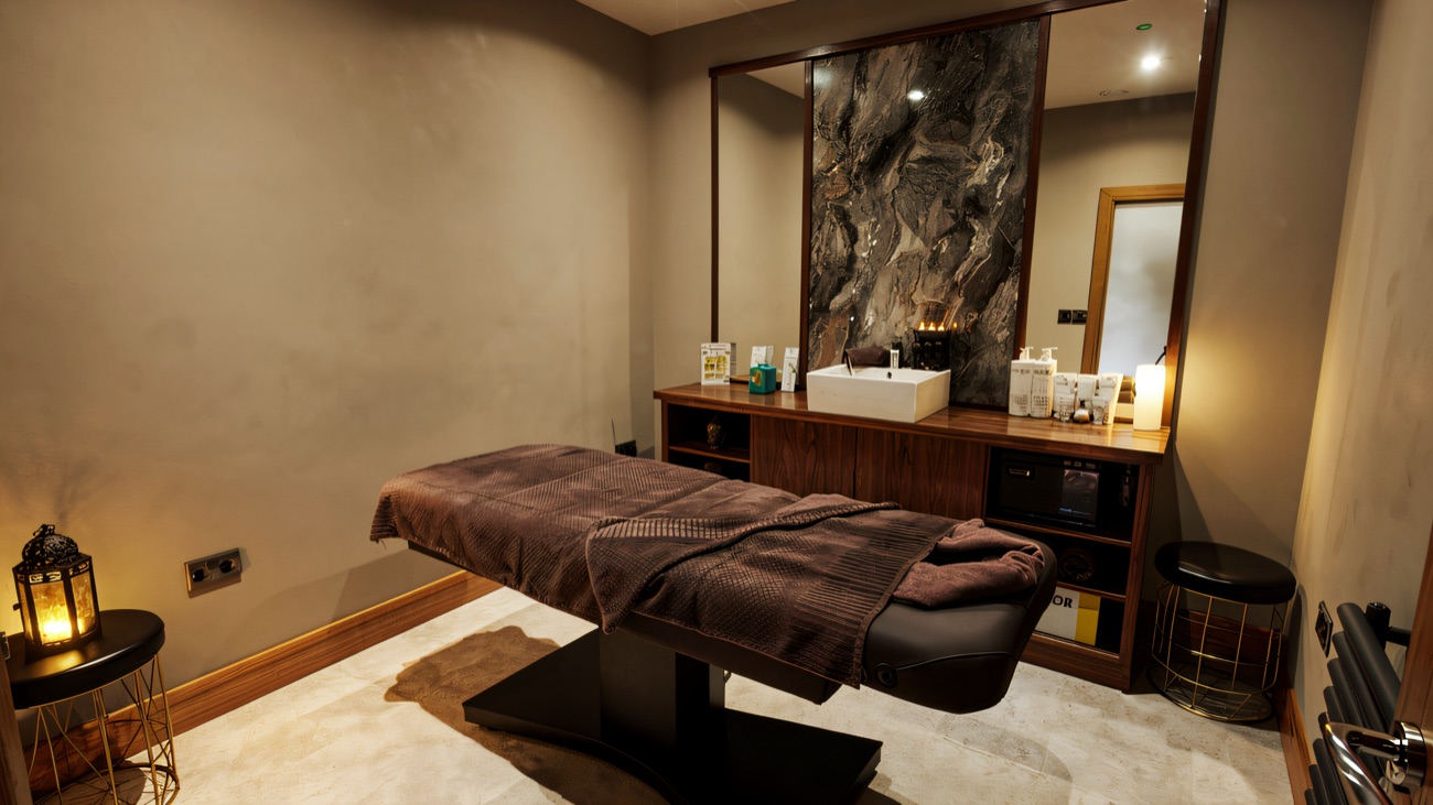 A candle-lit treatment room with a massage bed and Decléor products laid out.