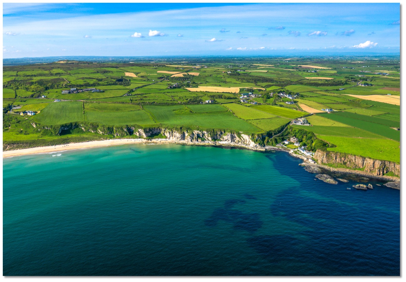 The green fields, cliffs and coastline around White Park Bay near Ballintoy from the air