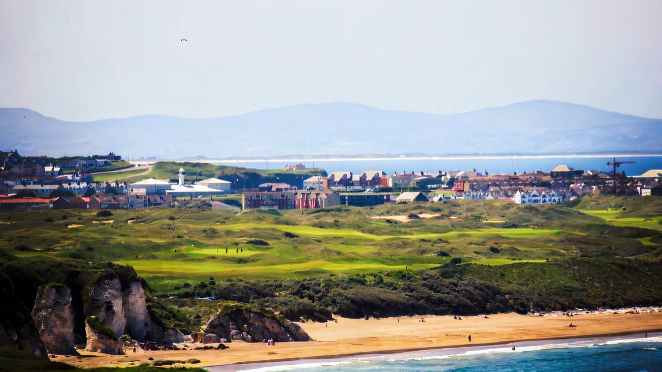 The chalk stacks at the end of the beach with the golf links and Portrush rooftops behind