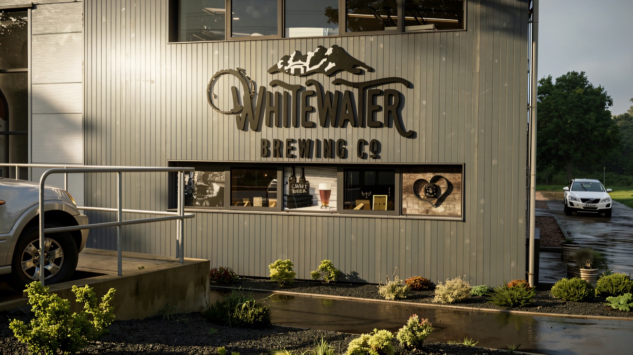 The grey-clad brewery building with its mountain-and-cottage sign, planting beds in front.