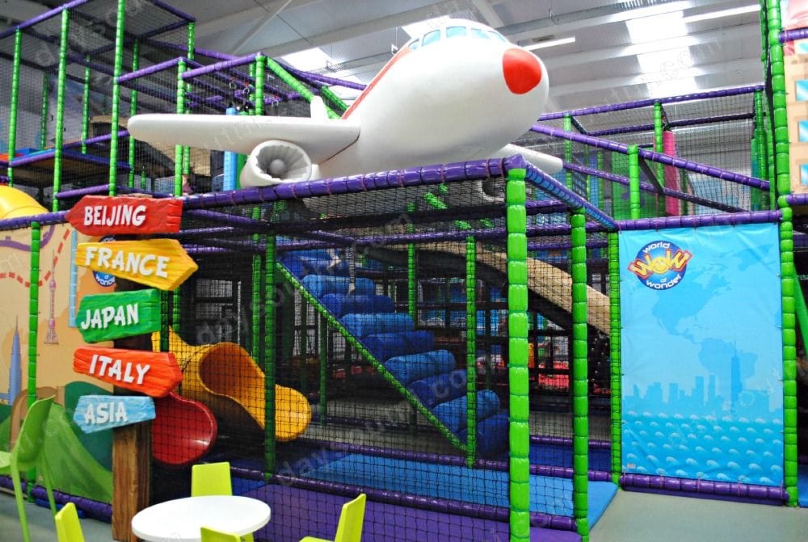 The global-adventure themed soft play at World of Wonder Carrickfergus, with an aeroplane on top of a green-and-purple frame and a country signpost