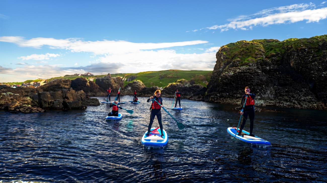 A paddleboard group threading through the rocky Causeway cove